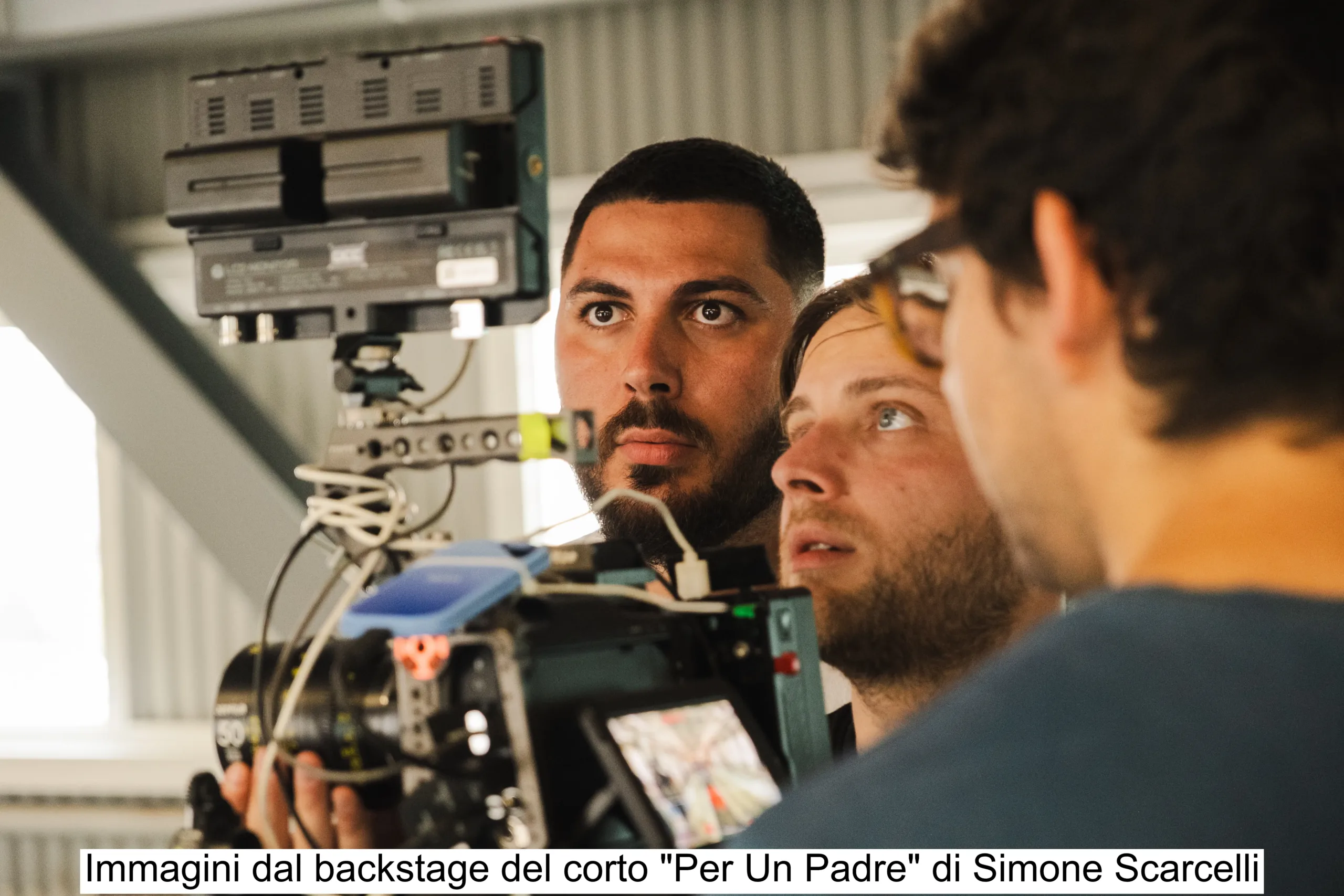 Corto-PUP-1 (1) “Foto backstage di un cortometraggio girato in un centro sportivo, con troupe e attori durante le riprese su un campo da calcio.”