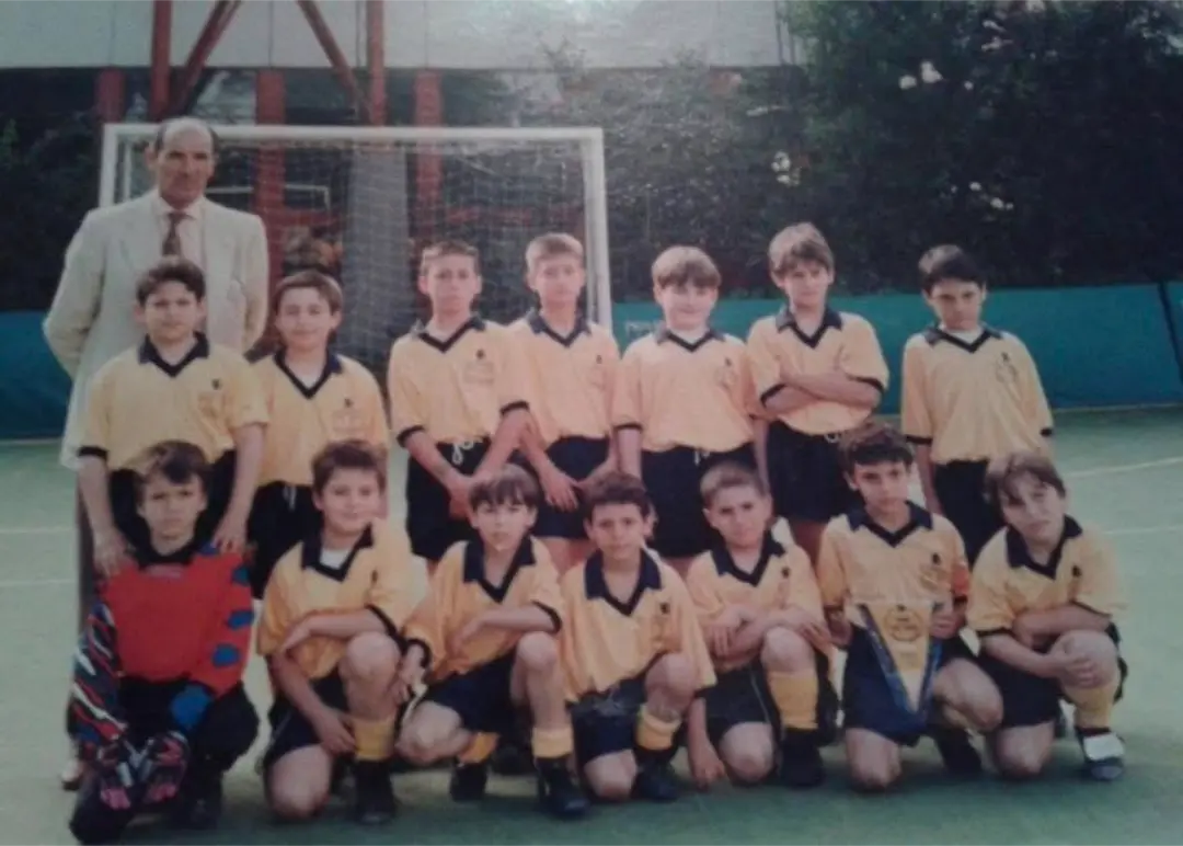 Squadra giovanile del Pian Due Torri con maglie gialle e pantaloncini scuri, in posa davanti alla porta insieme al proprio allenatore.